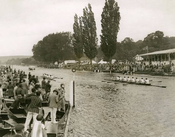 Vintage 1928 photograph of an eight-oared crew racing on the Henley regatta course, watched from the crowded bank